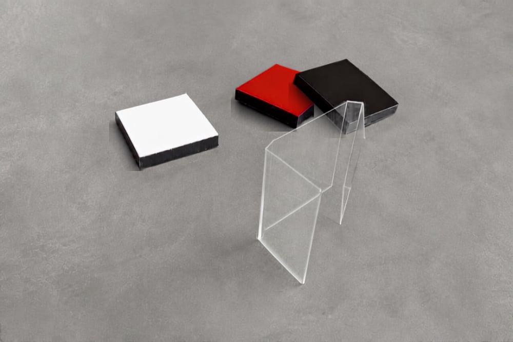 Trois tesselles — blanche, rouge, noire — et un étui transparent